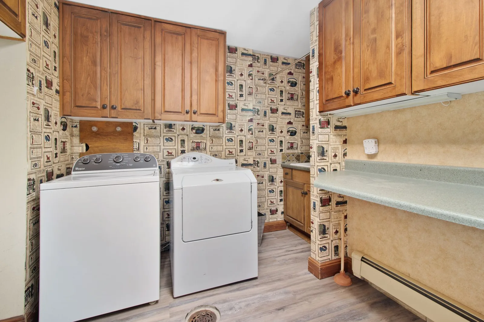 A laundry room with a washer and dryer beside wood cabinets