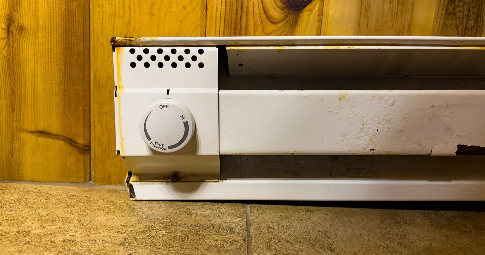 An electric baseboard heater with its thermostat knob