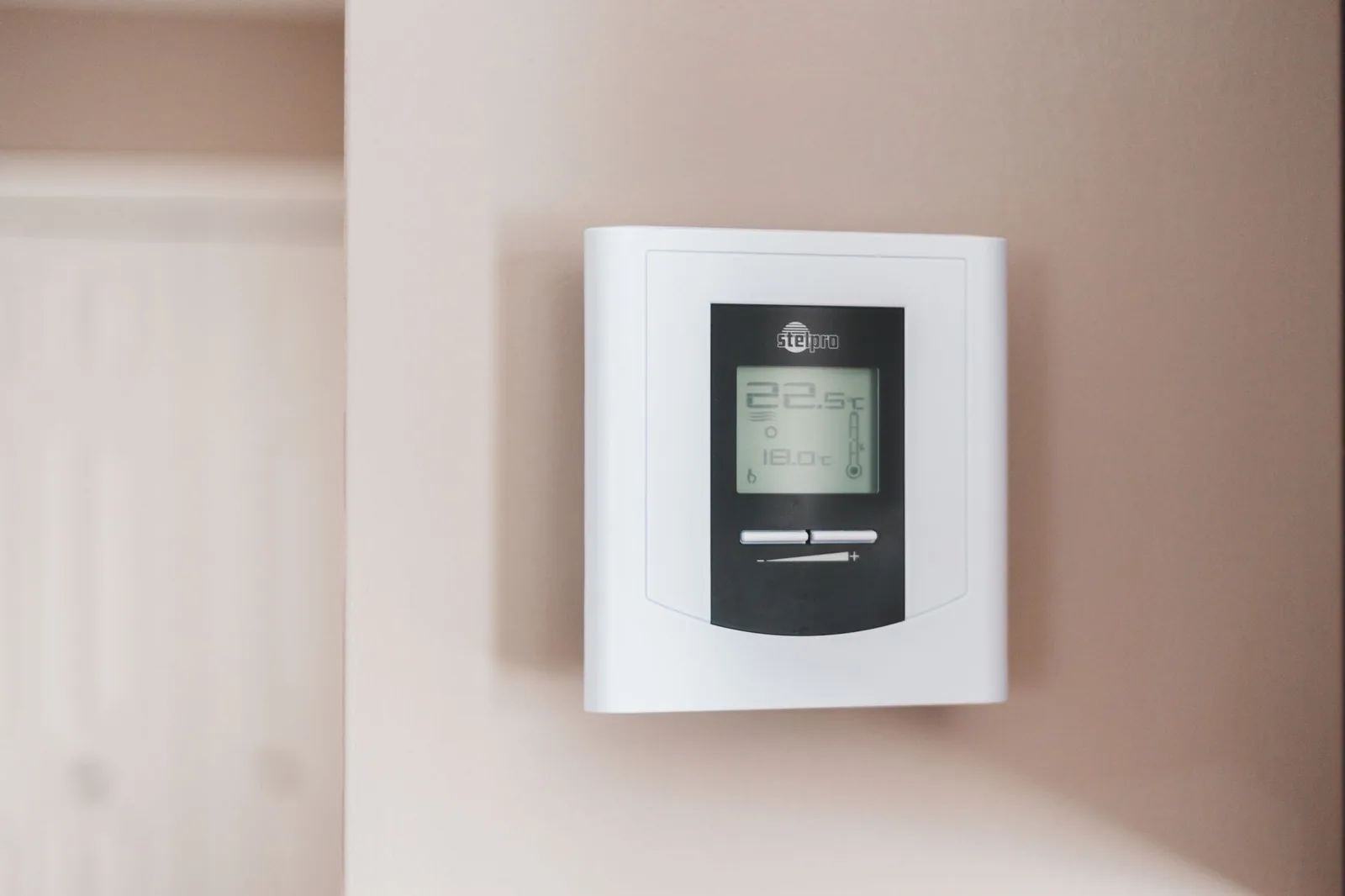 A digital line voltage thermostat on a wall