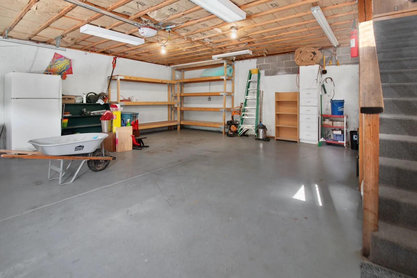 Garage with storage shelves and a wheelbarrow