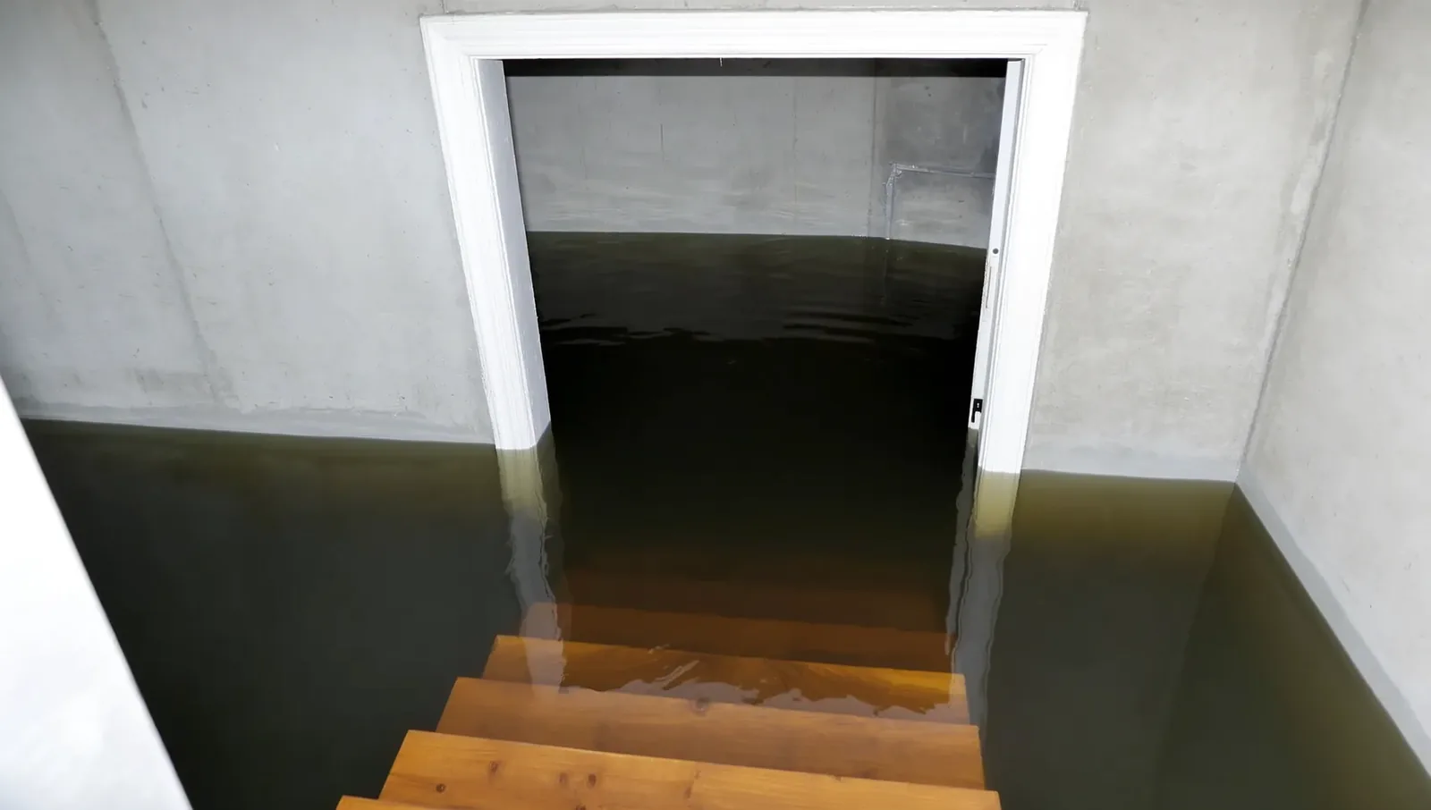 A basement staircase descending into dark standing floodwater that covers the entire lower floor.
