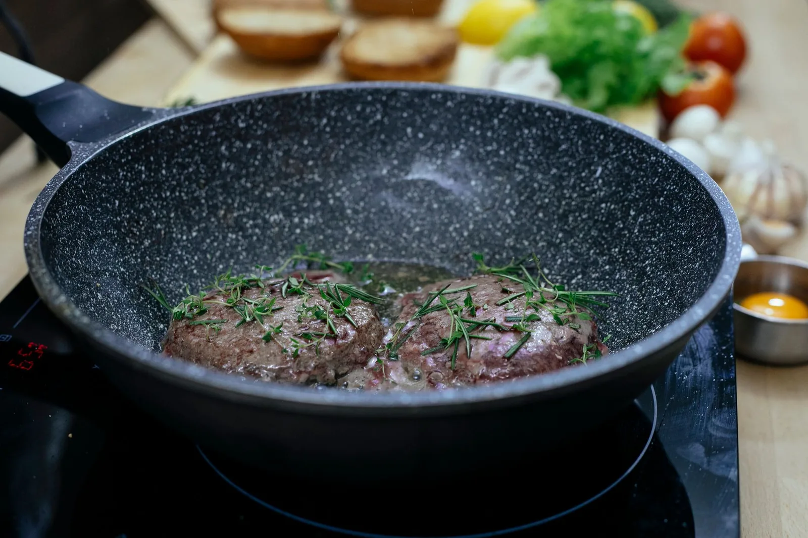 Burger patties frying in a pan on a cooktop