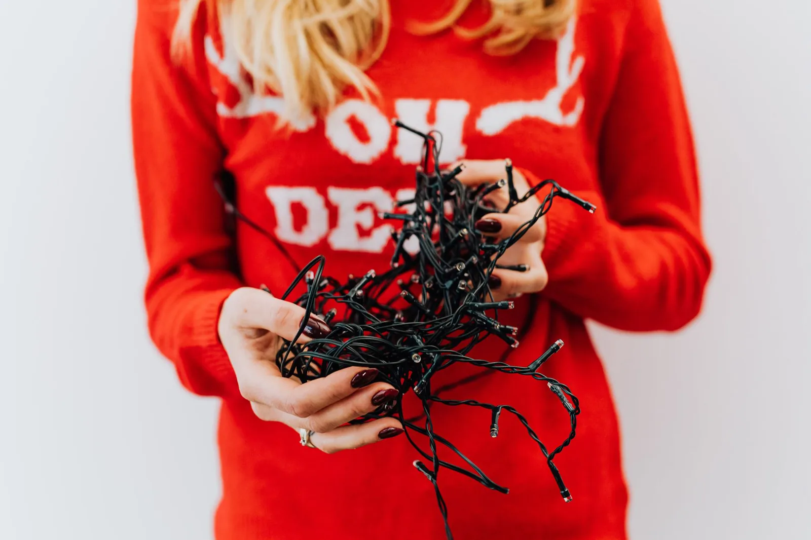 Hands holding a tangled string of holiday lights