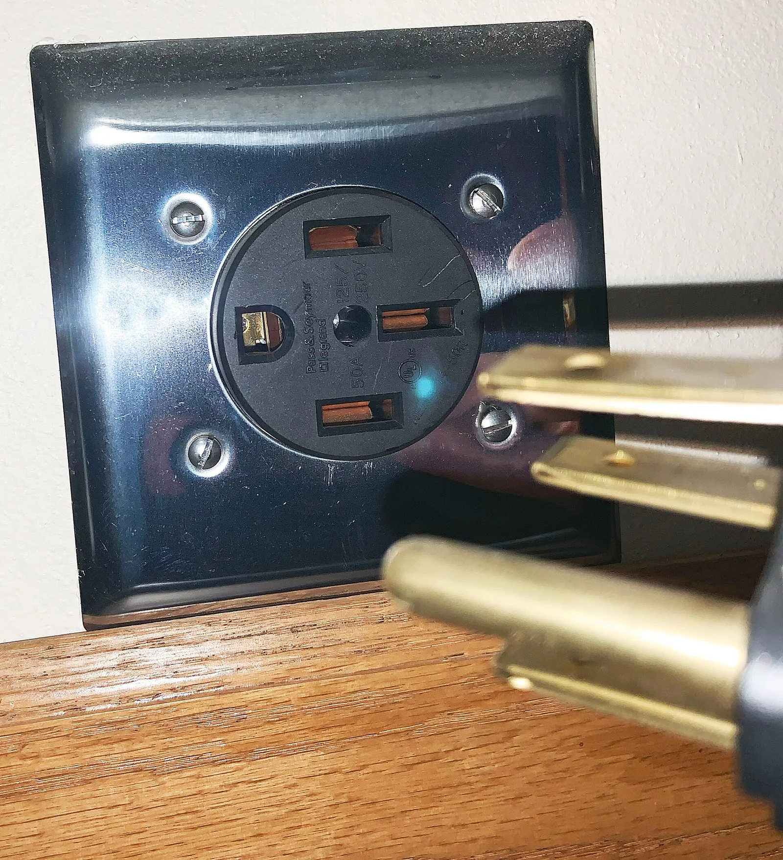 A NEMA 14-50 receptacle with a four prong plug being inserted