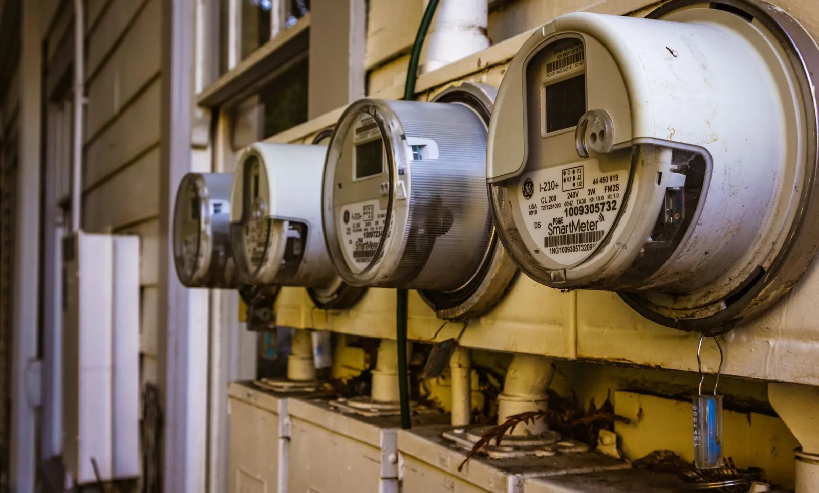 Four round electric meters on a house wall