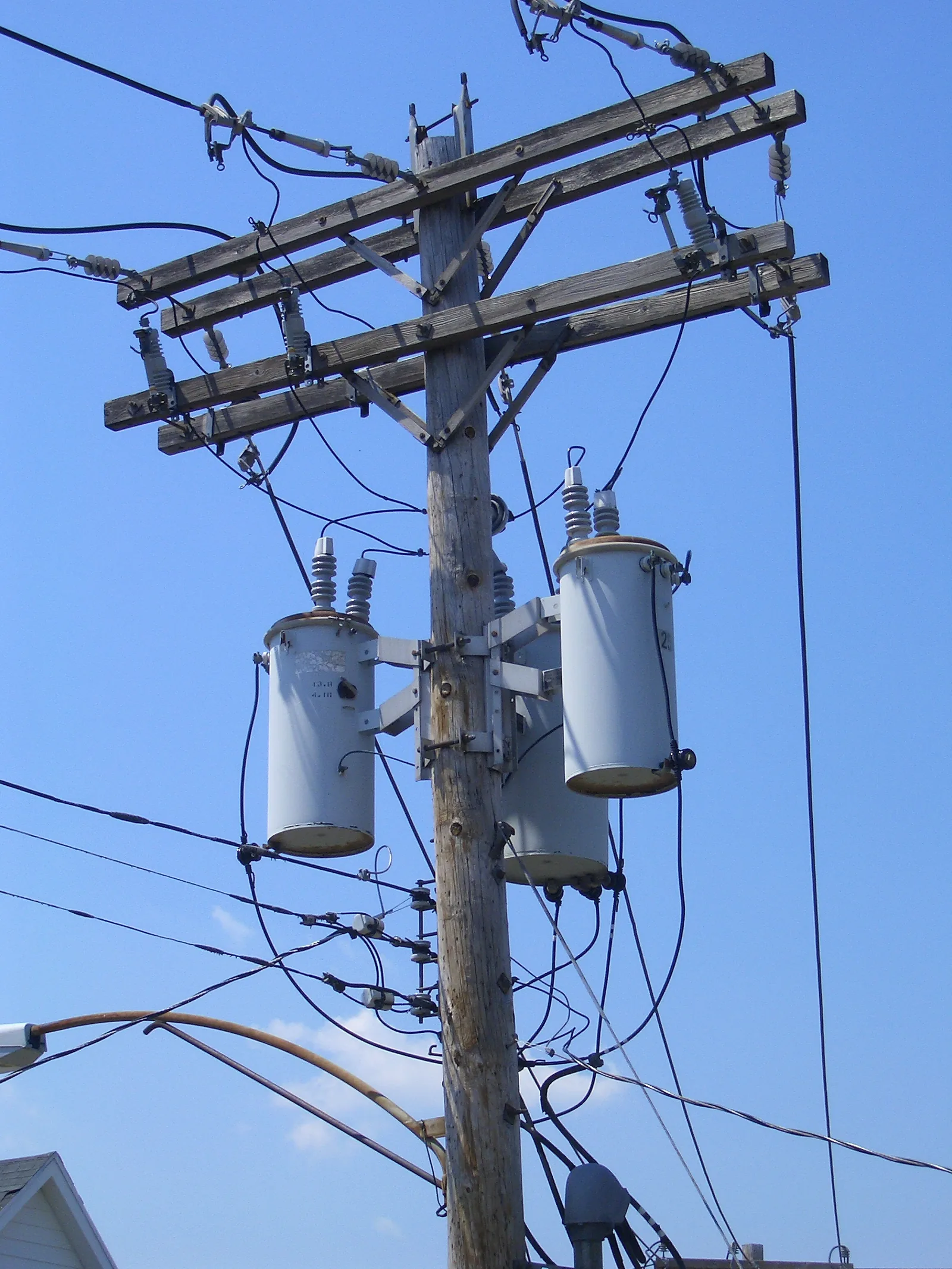 Three cylindrical transformers mounted on a wooden utility pole