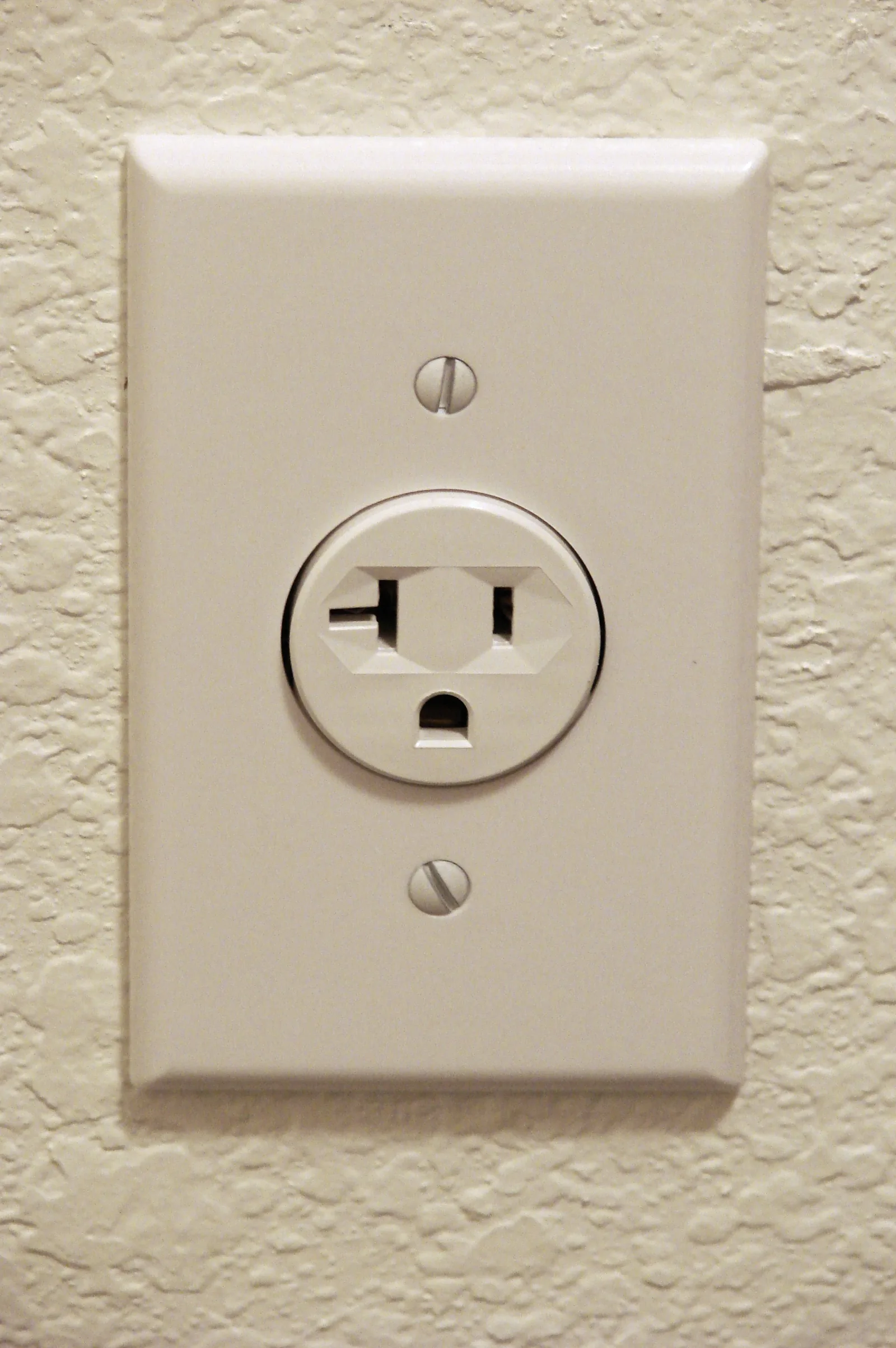 White three-prong wall outlet on a textured wall