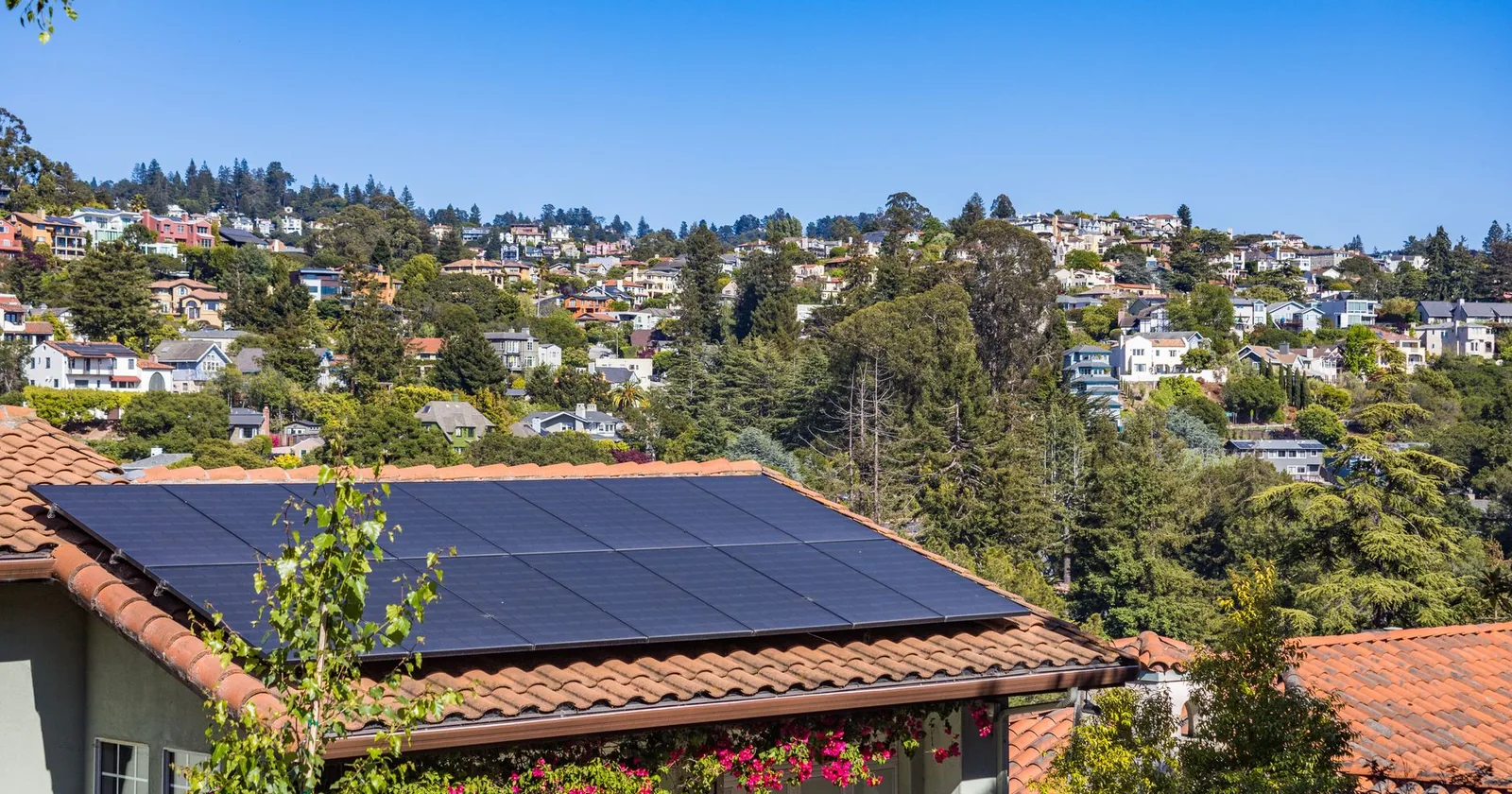 Solar panels on a tile roof above hillside homes