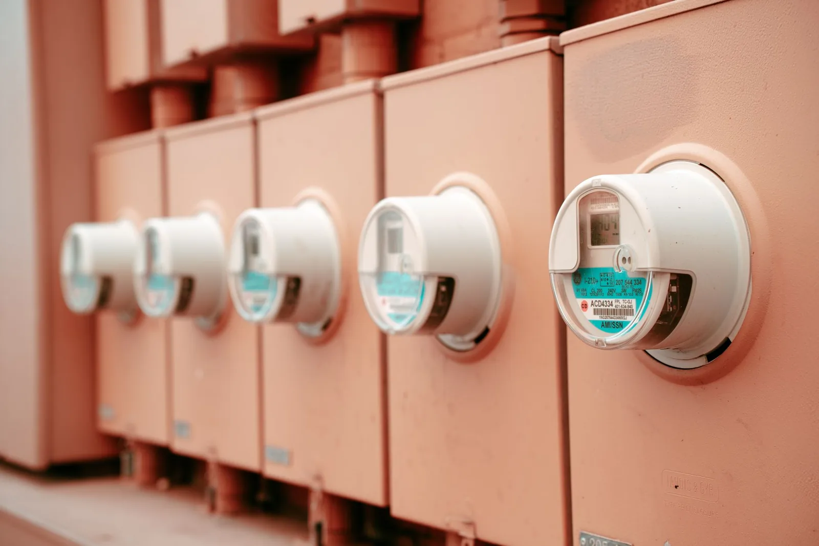 A row of round utility smart meters seated in painted meter enclosures on the exterior wall of a building.
