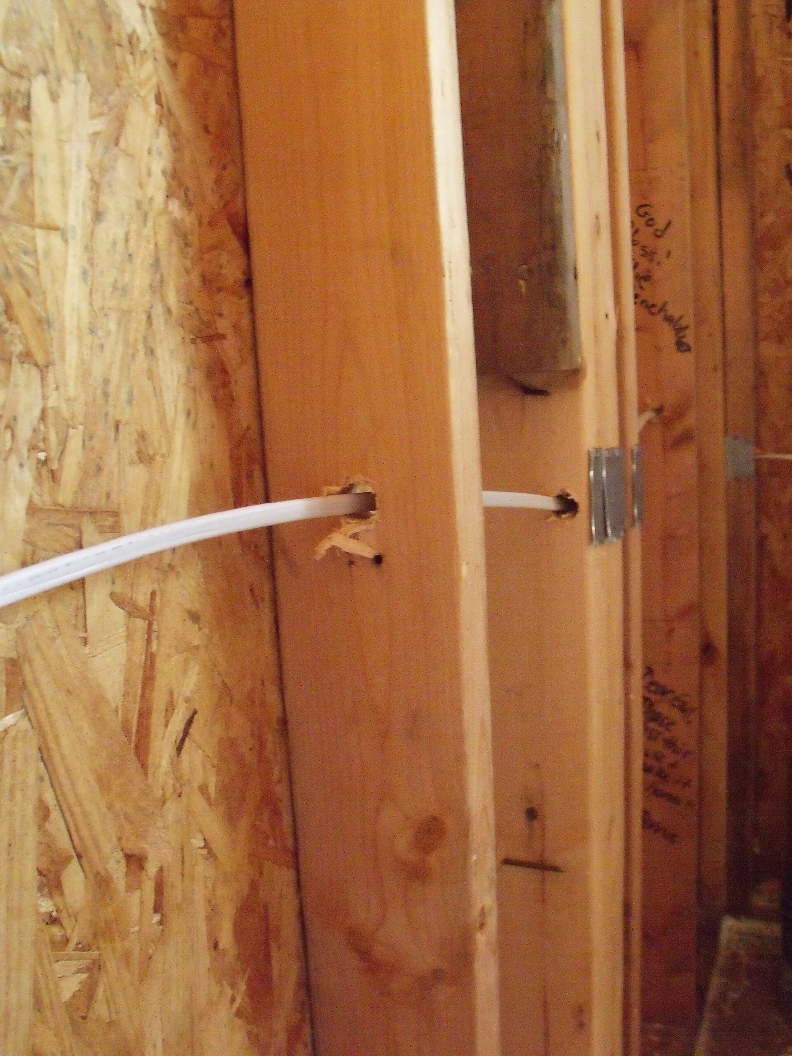 Cable through bored wood studs beside steel plates