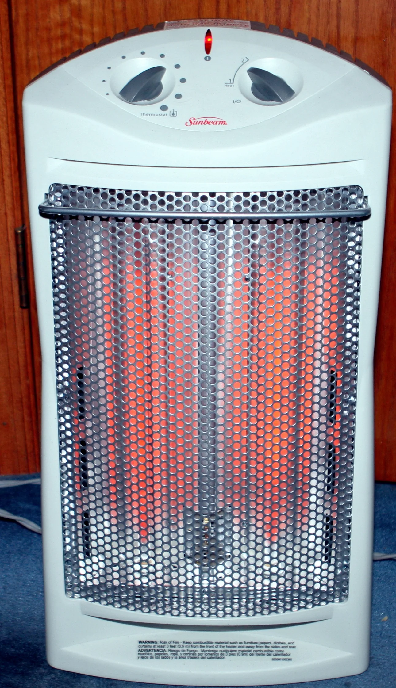 A white quartz space heater running with its elements glowing orange behind a metal grille.